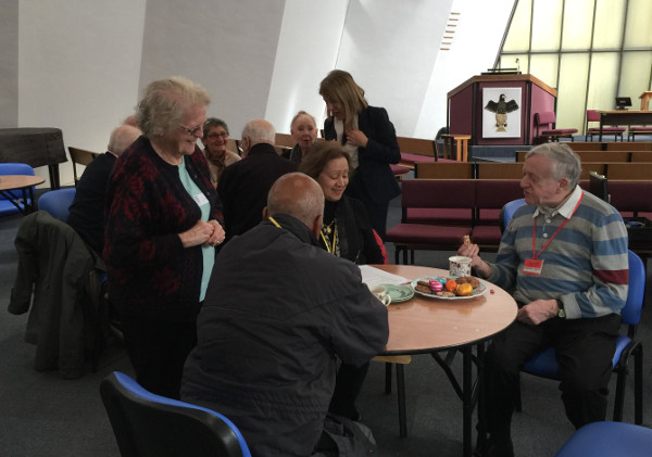 Members concentrating on the quiz with a cake and tea.