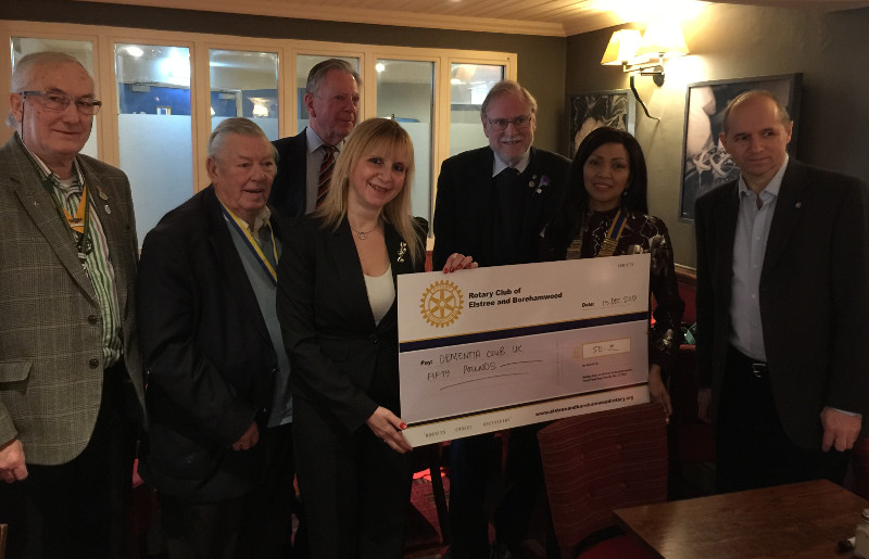 Members of the Rotary Club of Elstree & Borehamwood donating a cheque to Lisa chairman of Dementia Club UK